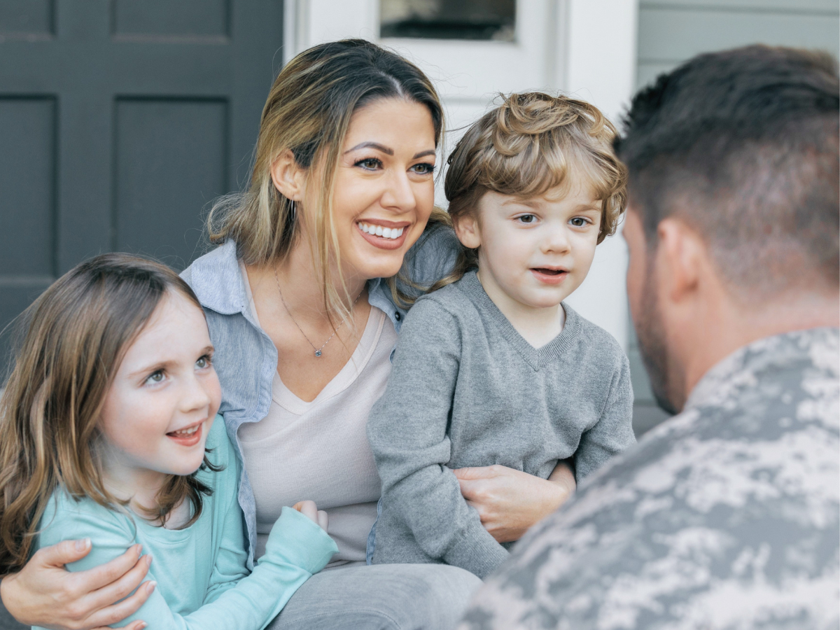 military family sitting in front of house